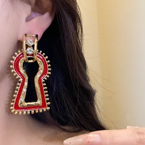 Close-up detail of retro palace style keyhole earrings with red enamel and crystals