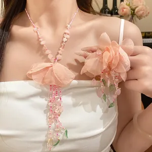 Vue détaillée d'un collier à pompon fleur en perles roses de style Mori sur modèle