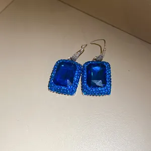 Detailansicht eleganter rechteckiger blauer Edelstein-Ohrringe mit Kristall-Halo