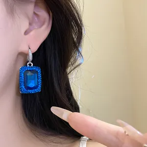 Detaillierte Ansicht luxuriöser quadratischer blauer Edelsteinohrringe mit Pavé-Rand.