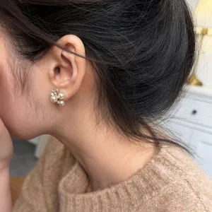 Detailed macro view of cluster pearl stud earrings with zircon accents on an Asian model