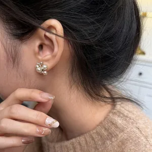 Detail view of elegant cluster pearl earrings with zircon accents on a model's ear