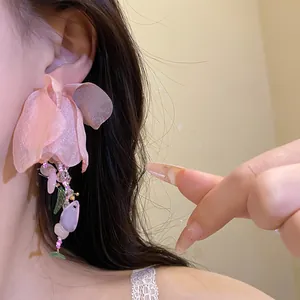 Gros plan d'une boucle d'oreille fleur rose avec gland en perles, style Mori.