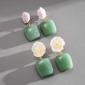 Detalle de pendientes de flores de resina y esfera con colgantes cuadrados verdes