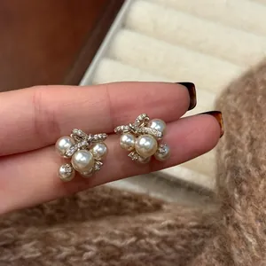 Detailed close-up shot of elegant pearl cluster stud earrings with zircon bow accents