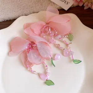 Vue détaillée de boucles d'oreilles fleurs en maille rose avec pompons perlés