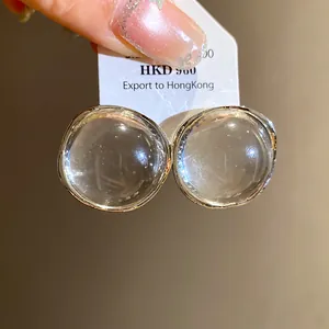 Close-up of minimalist round transparent resin stud earrings with silver rims