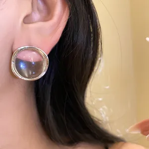 Close-up view of minimalist round transparent resin stud earrings with silver needles