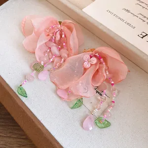 Gros plan sur des pétales en tissu rose et des glands perlés avec feuilles