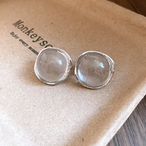 Macro view showing the clear resin texture of round stud earrings with silver edges