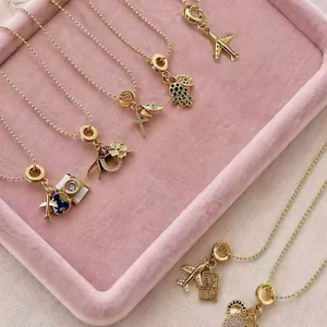 Parure de colliers dorés thème voyage avec pendentifs avion et terre sur plateau velours
