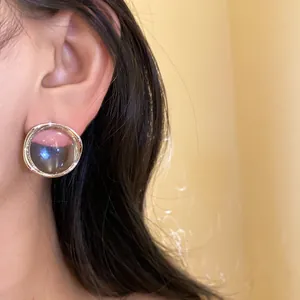 Close-up of a minimalist pink and smoky grey resin round stud earring worn on ear