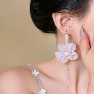 Close-up detail of French style pink chiffon flower earrings with pearls on a model