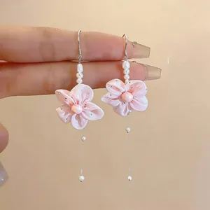 Close-up detail of handmade pink chiffon flower earrings with pearl accents and long drops.
