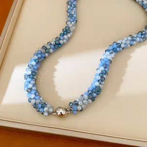 Détail exquis d'un collier de perles en verre bleu et blanc avec un fermoir magnétique.