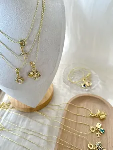 Détail de colliers plaqués or avec breloques avion et globe dans un présentoir à bijoux.