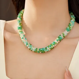 Gros plan d'un collier en perles de verre vertes et blanches sur la clavicule d'un mannequin