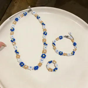 Handmade beaded flower jewelry set with necklace, bracelet, and ring in blue and white