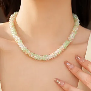 Gros plan d'un collier en perles de verre vertes et champagne sur le cou d'un modèle