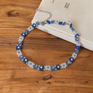 Detailed macro view of blue and white beaded flower necklace displayed on a wooden surface