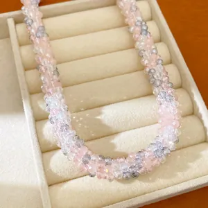 Vue détaillée d'un collier en perles de verre pastel dans un plateau à bijoux en velours