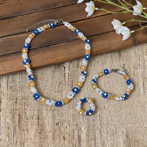 Handmade beaded flower jewelry set with necklace, bracelet, and ring in blue and white colors.