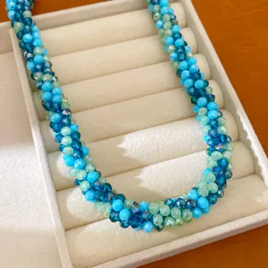 Gros plan d'un collier de perles de verre facettées bleues et vertes dans une boîte