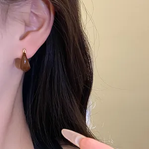 Close-up of vintage resin drip oil teardrop earring in amber brown and gold