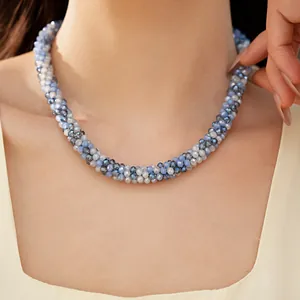 Gros plan détaillé montrant un collier magnétique en perles de verre bleues et grises sur cou.