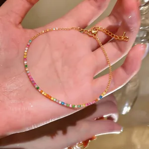 Detailed close-up of a gold-tone rainbow cubic zirconia tennis bracelet held in hand