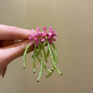 Detailed view of pink beaded flower earrings featuring elegant green beaded tassels.