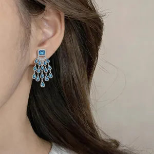 Detailed macro shot of vintage blue teardrop chandelier earrings featuring rhinestones on ear