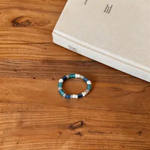 Detail view of a Korean ins style beaded bracelet with blue and white beads on wood.