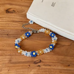 Close-up of colorful flower beaded necklace with stainless steel chain on wooden background.