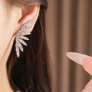 Close-up of a sparkling 18K gold plated cubic zirconia wing ear cuff on an ear.