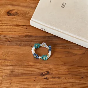 Close-up of a Korean style flower beaded ring with blue and green acrylic petals.