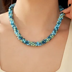 Vue détaillée d'un collier ras du cou en perles de verre tressées aux tons bleus d'été.