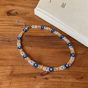 Close-up detail of a colorful Korean style beaded flower necklace on a rustic wooden table
