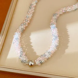 Détail d'un collier de perles de verre roses et grises avec un fermoir magnétique argenté