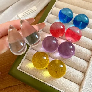 Dettaglio di orecchini a bottone in resina colorata a forma di goccia e sfera.