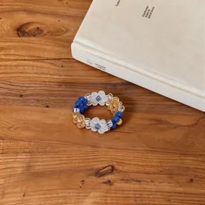 Detail view of a colorful handmade flower beaded bracelet on a wooden table.
