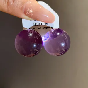Dettaglio di eleganti orecchini a lobo in resina viola tonda con perni in argento