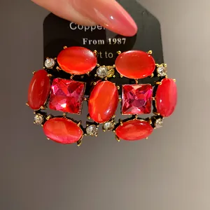 Primo piano di orecchini vintage con pietre occhio di gatto rosse e cristalli rosa