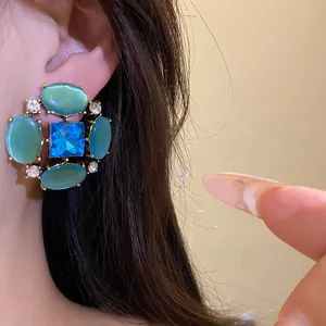 Primo piano di orecchini vintage con strass e occhio di gatto e pietre preziose blu.