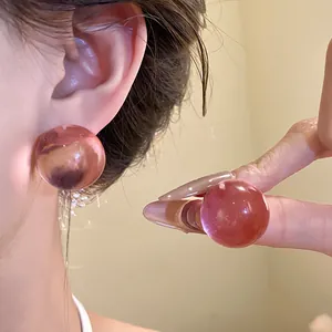 Primo piano di orecchini a bottone a sfera in resina rosa per un look molto elegante