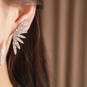 Detailed view of a sparkling cubic zirconia wing ear cuff climbing the model's ear