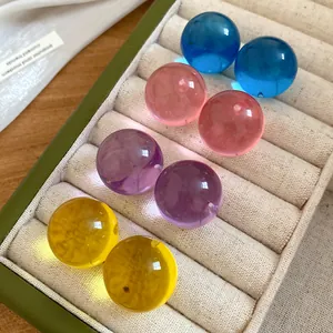 Dettaglio di orecchini a sfera in resina colorata disposti in un portagioie