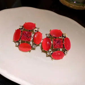 Dettaglio di orecchini vintage stile palazzo con pietre occhio di gatto rosse e strass.