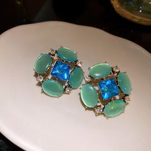 Primo piano di orecchini vintage in stile palazzo con pietre occhio di gatto verde e blu