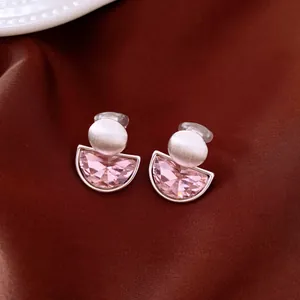 Close-up of pink semi-circular clip-on earrings with textured silver ball on satin.